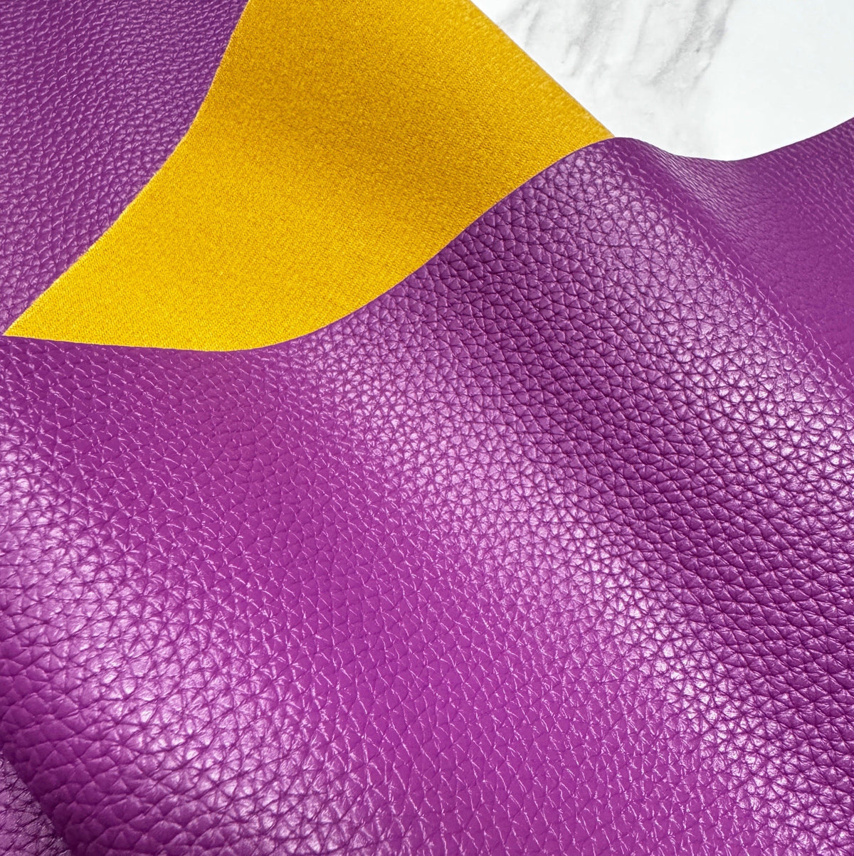 Textured purple faux leather vinyl sheet with yellow underside.