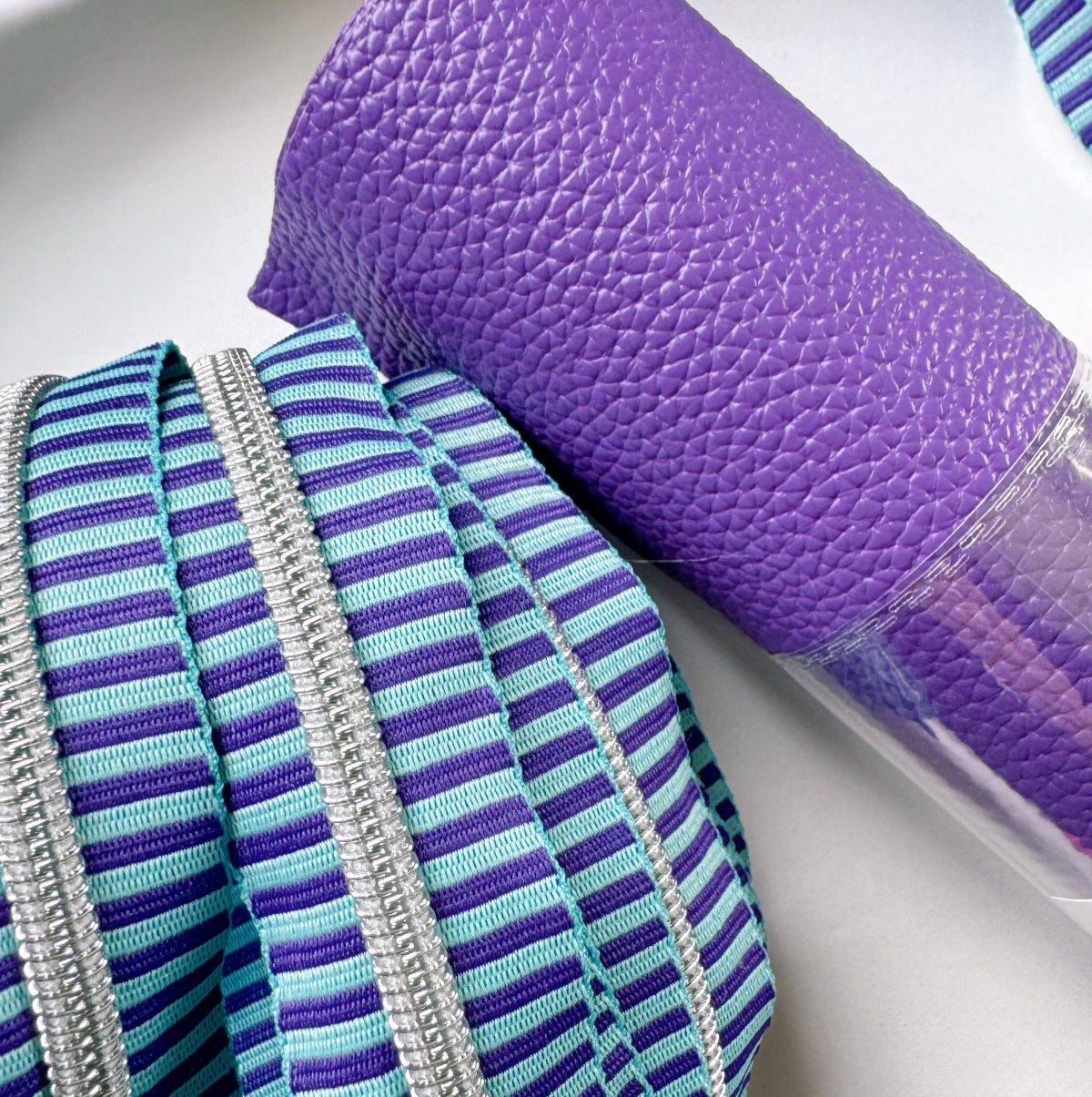 Close-up of a purple textured mat and striped blue and purple fabric on a white surface