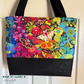 Tote bag in Alison Glass Art Theory Night wideback with colorful moths and flowers on black, with a black cork base