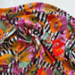 Spice Fusion Stripes rayon fabric by Art Gallery Fabrics featuring large orange, pink, and mint poppies layered over vertical black and white stripes. This soft, 100% rayon fabric has a fluid, silky drape ideal for sewing garments like dresses, tunics, and pants.