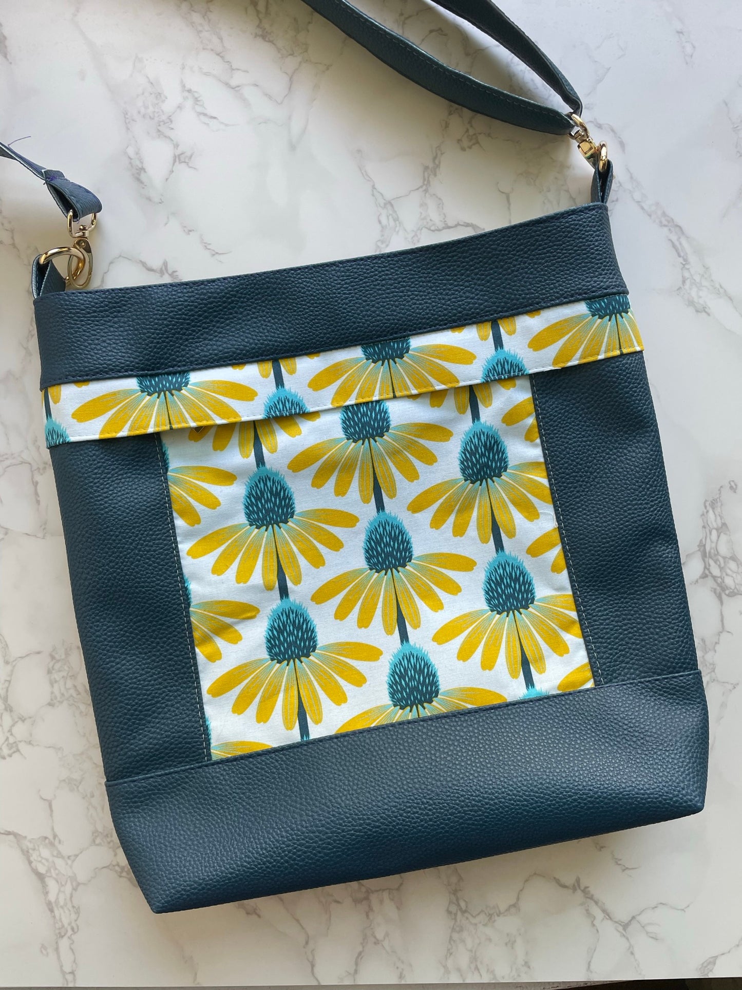 Aspen Crossbody Bag pattern by Emmaline Bags displayed with stylish finished crossbody bag sample in green moonglow vinyland yellow floral accent