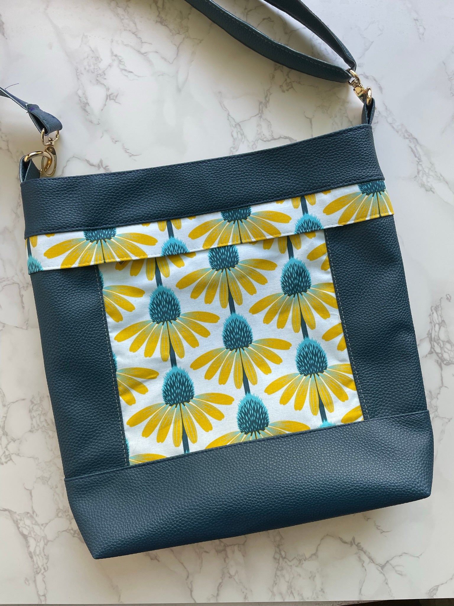 Aspen Crossbody Bag pattern by Emmaline Bags displayed with stylish finished crossbody bag sample in green moonglow vinyland yellow floral accent