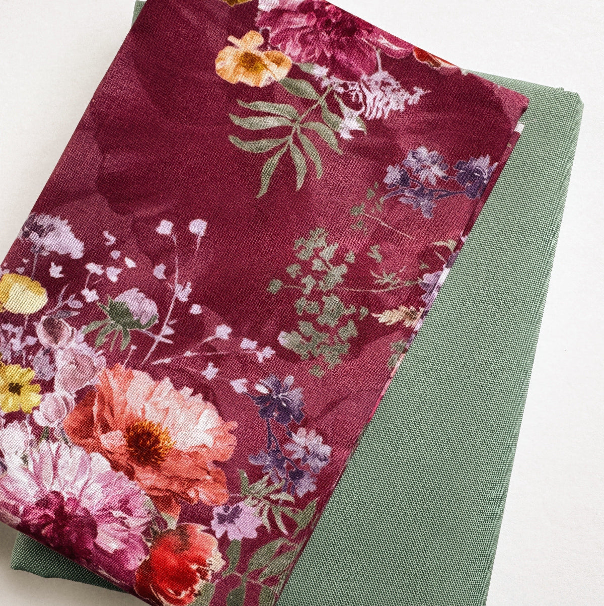 Floral fabric with a deep red background on a green surface