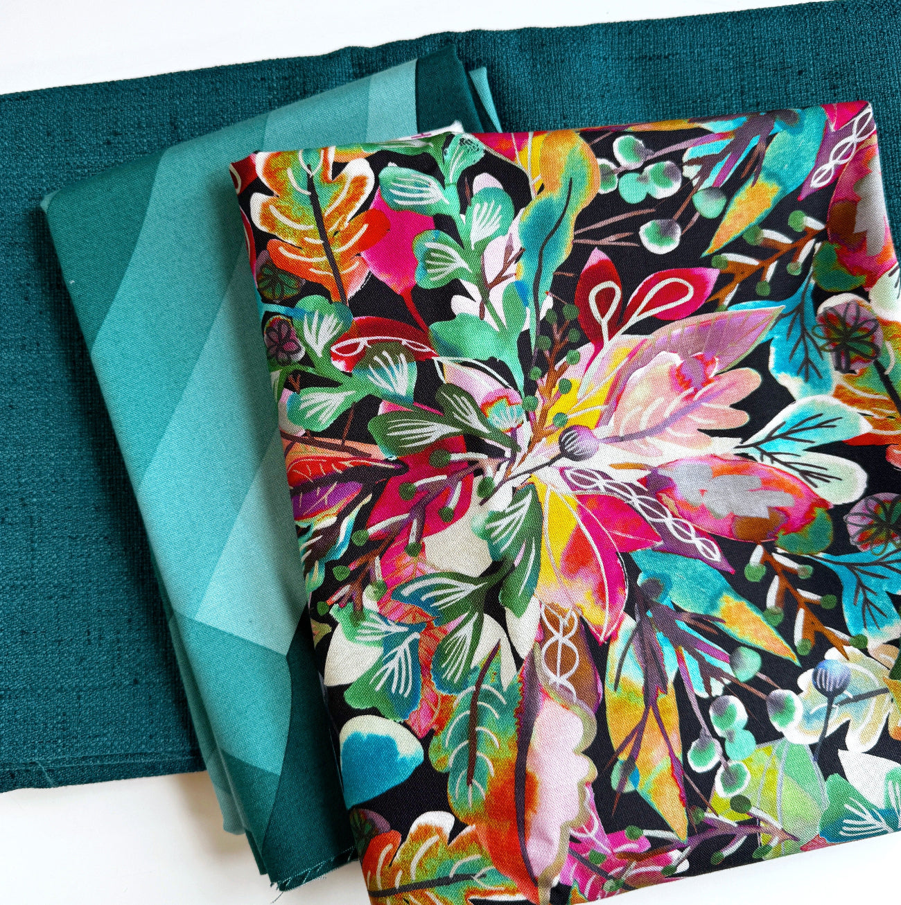 Vibrant multi-color abstract botanical floral fabric bundle curated with a teal geometric chevron pattern fabric and a matching dark teal textured linen cotton fabric for sewing projects.
