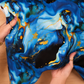 Blue and gold marbled fabric held by hands on a wooden surface