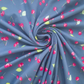 A close-up of blue-gray fabric arranged in a spiral, printed with a repeating pattern of bright red cherries and small green leaves.