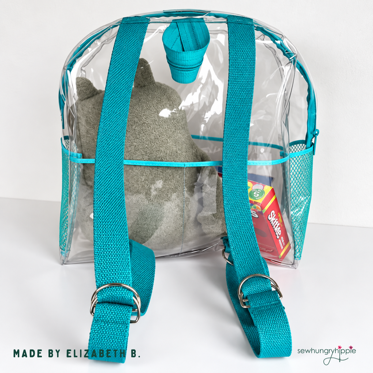 Back of clear vinyl backpack showing teal webbing shoulder straps, made by Elizabeth B.