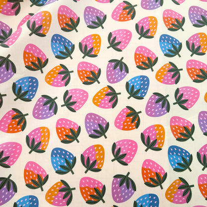 A close-up of a fabric or paper material featuring a colorful repeating strawberry pattern on a cream background.