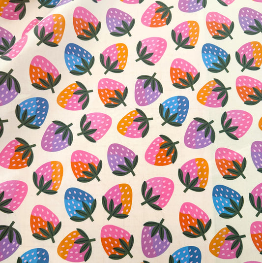 A close-up of a fabric or paper material featuring a colorful repeating strawberry pattern on a cream background.