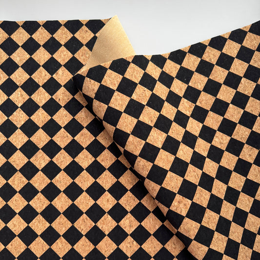 A close-up of a black and tan checkered pattern, likely cork or cork-like material, folded over to show the reverse side on a light gray background.