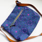 Blue patterned bag with brown strap on a white background