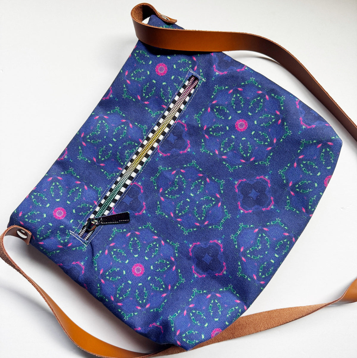 Blue patterned bag with brown strap on a white background