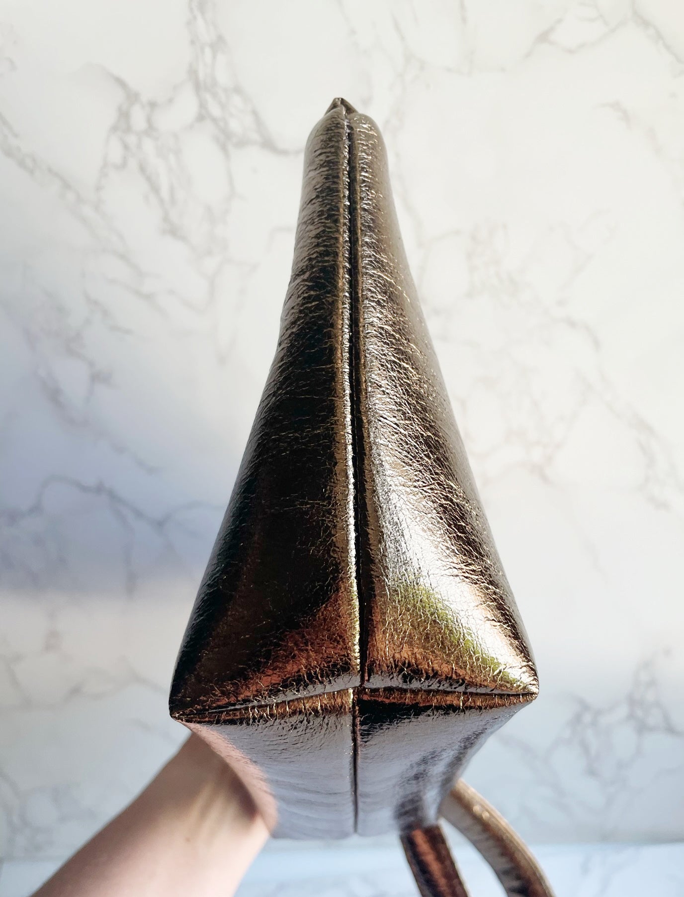 Bronze handbag on a marble surface.