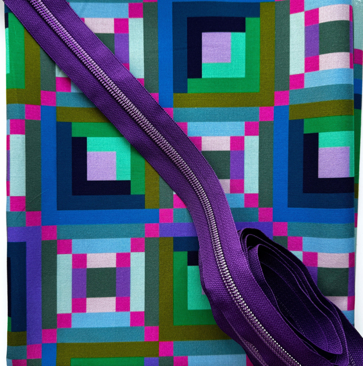 A yard of Log Cabin Periwinkle Fabric designed by Annabel Wrigley for Windham Fabrics and a three yards purple zipper tape in purple teeth