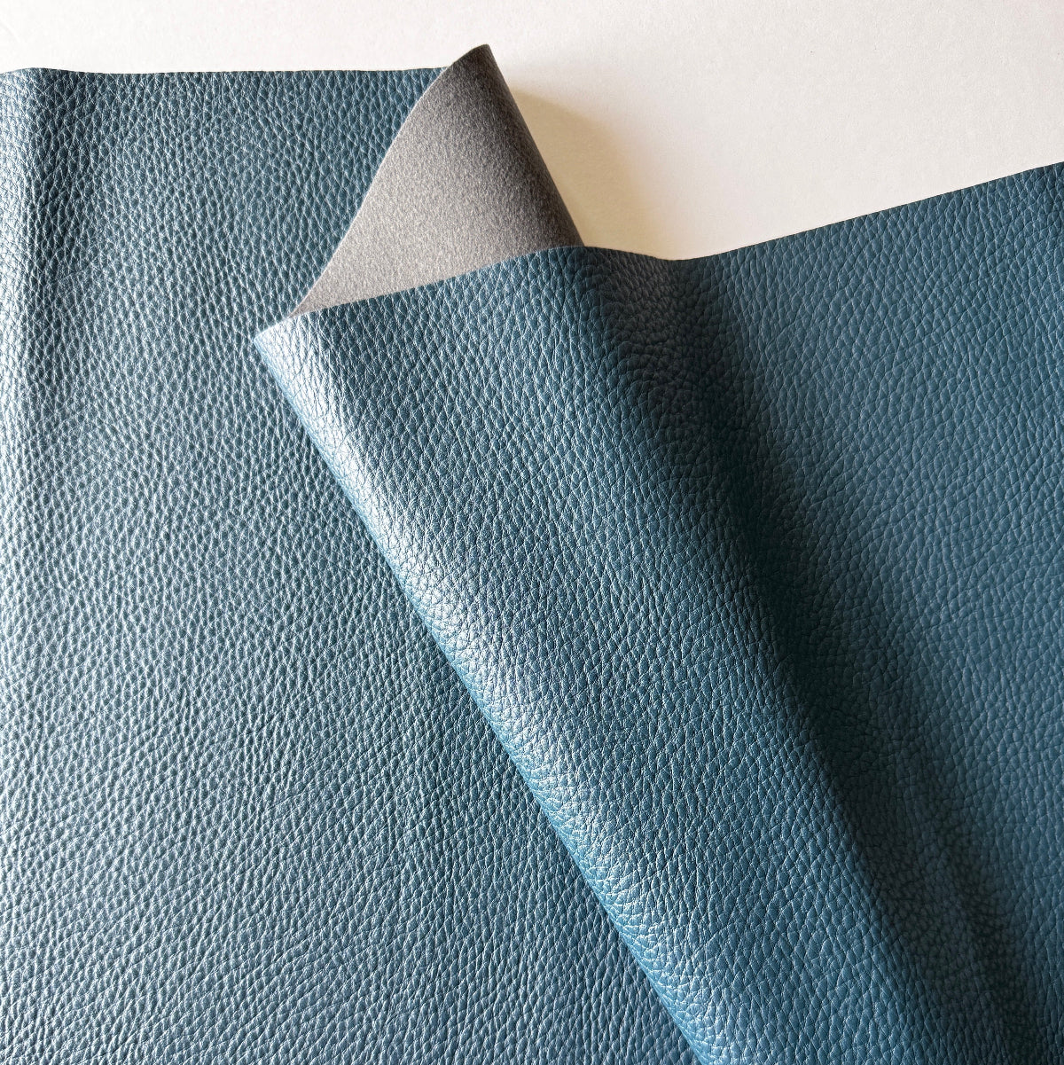 Blue faux-leather fabric with a textured surface on a white background