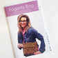 Front cover of a printed sewing pattern booklet titled "Fogerty Bag: crossbody bag with pockets" by Natalie Santini (@sewhungryhippie). The booklet has a pink top banner and a photo of a smiling woman in a denim jacket wearing a rectangular crossbody bag with a leopard print pattern and front pockets.