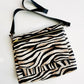 Zebra print crossbody bag with black strap.