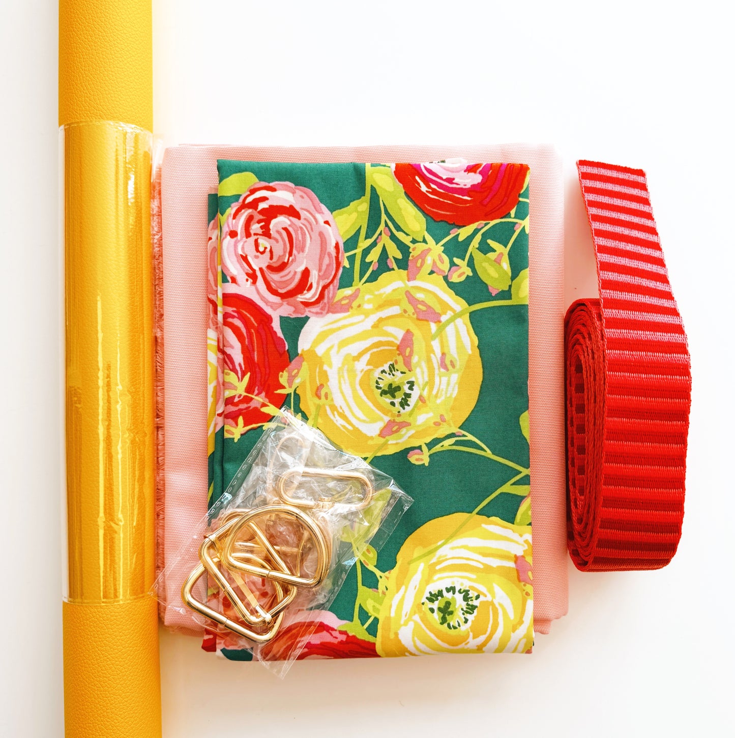 Yellow and pink Joni bag making kit with floral fabric, vinyl roll, hardware, webbing, and water resistant canvas