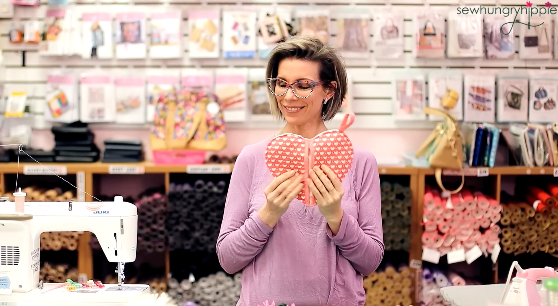 Natalie holding a heart-shaped pink pot holder in the Sew Hungry Hippie sewing studio