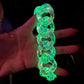Person holding a folded neon green glow-in-the-dark chunky plastic chain bag strap or necklace under UV light.