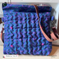Stack of blue fabric with pink and green patterns on a sewing machine station