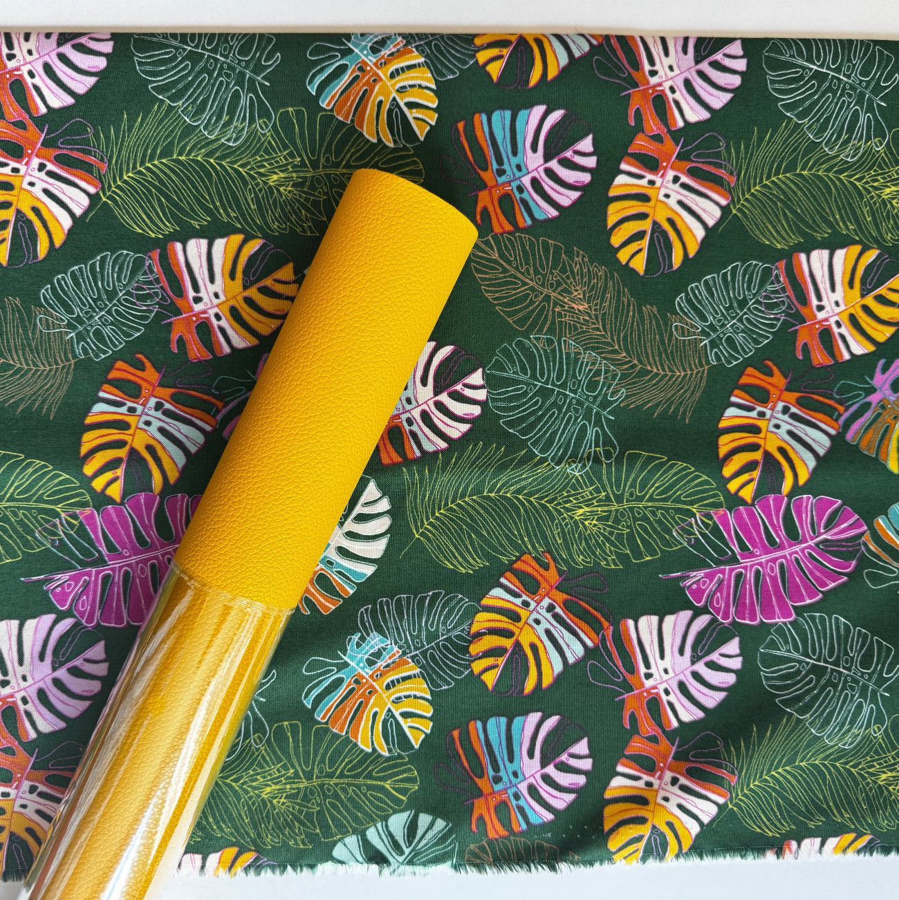 This is the Art Gallery Fabrics "Jungle Tour" print from the Maara collection designed by Alexandra Bordallo, featuring a vibrant, multi-colored leaf pattern on a dark green cotton background