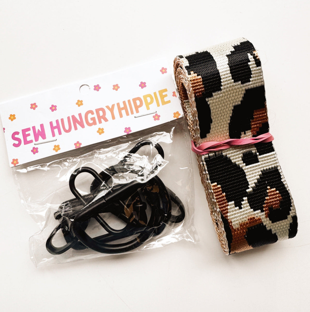 A roll of leopard-print woven nylon webbing and black hardware accessories from SewHungryhippie.