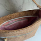 Cork handbag with zipper and pink interior against marble background.