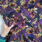 Hand holding a piece of Robert Kaufman Midnight Purple Dreadful Delights fabric to show the scale of the gothic skull, owl, and floral pattern.