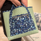 Bag in sage green quilted vinyl with a blue mosaic print front pocket