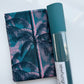 A flat-lay view of the craft materials for the Match Up #3 package, showing a folded piece of Ruby Star fabric with a palm tree pattern next to a rolled sheet of teal textured vinyl labeled "sewhungryhippie".
