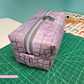 A rectangular zippered pouch with a purple and lavender faux-croc pattern, resting on a green cutting mat.
