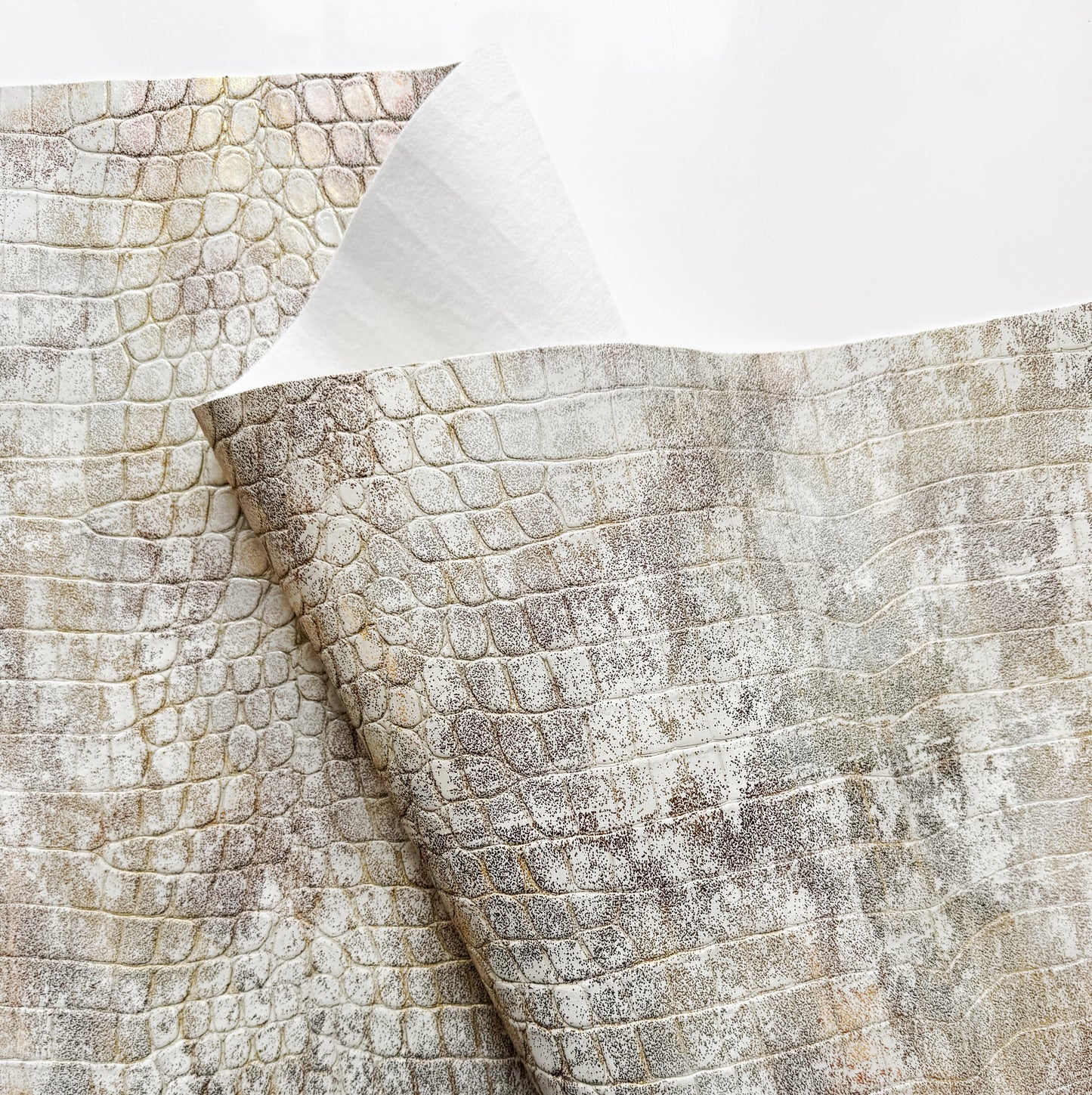 Textured reptile croc vinyl in cream and beige colors for bag making on a white background
