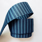 A close-up shot of a 2-inch wide, heavy-duty woven fabric webbing strap on a white background. The strap features horizontal stripes alternating between dark navy blue and a lighter slate blue. The webbing is folded into a loose, architectural loop, highlighting its thick, ribbed tactical texture ideal for durable bag straps, tote handles, and backpacks.