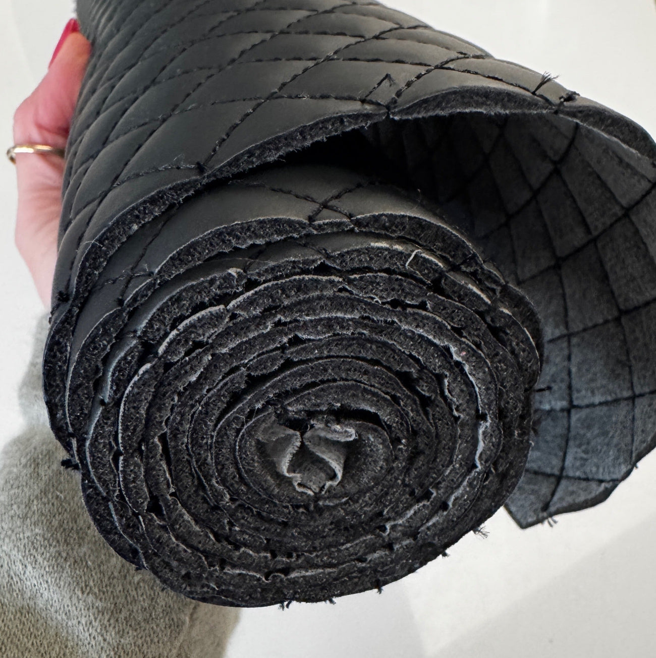Quilted black vinyl fabric roll with padded texture for bag making projects