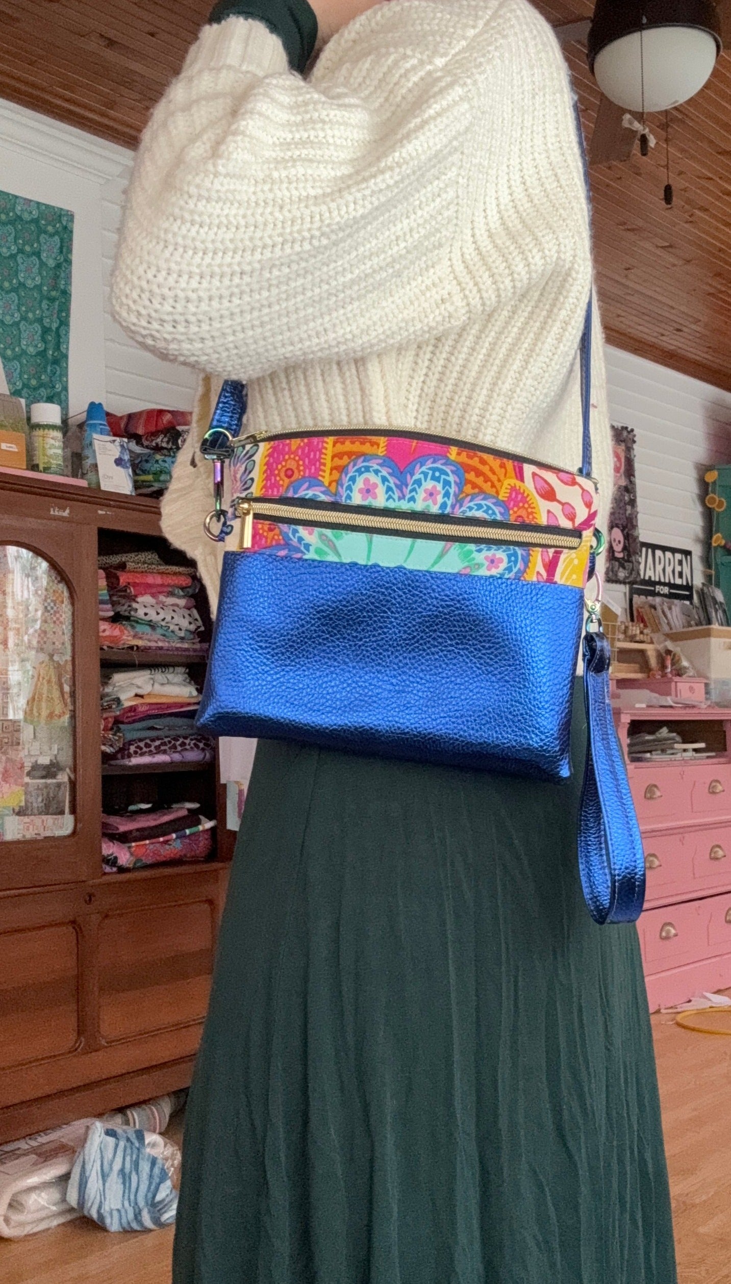Woman wearing a sweater and skirt, holding a blue and patterned purse.