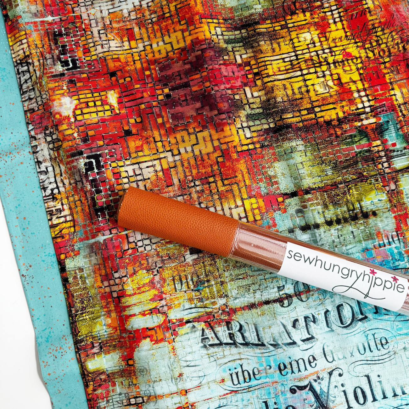 Sewing fabrics and vinyl 'sewhungryhippie' label on a textured surface with colorful abstract design