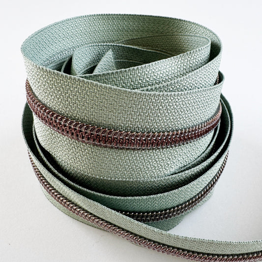 Sage green nylon zipper tape with silver teeth.