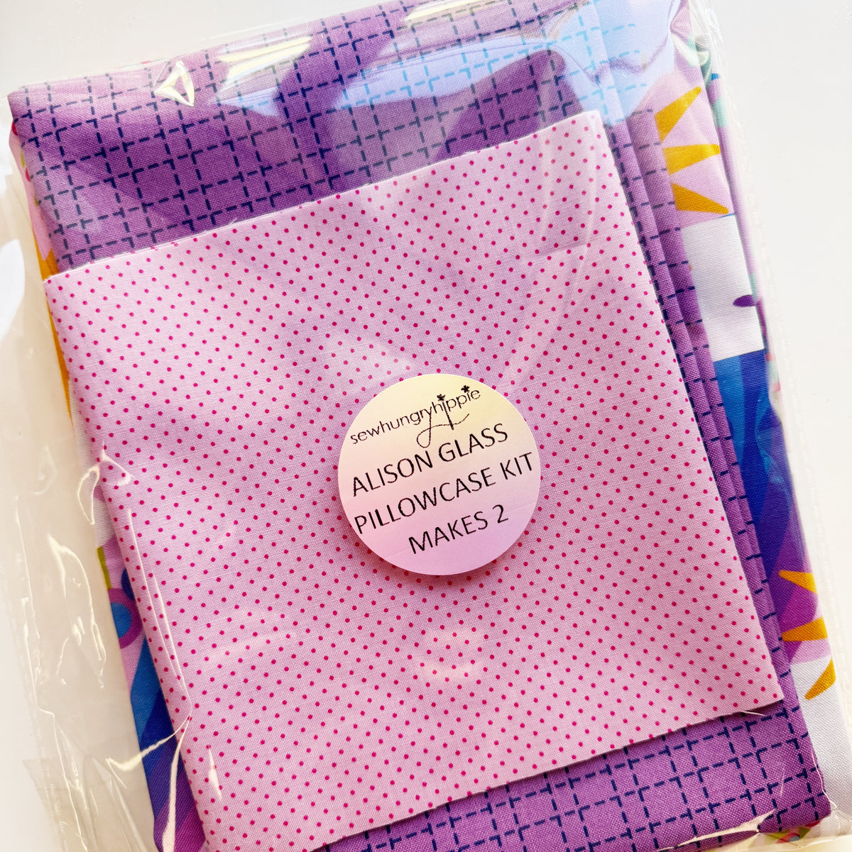 An unopened Sew Hungry Hippie sewing kit featuring Alison Glass fabrics in shades of purple and pink polka dots, labeled "Alison Glass Pillowcase Kit Makes 2."