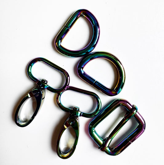 Five metallic carabiner-style keyring clips with a glossy iridescent rainbow finish, arranged on a plain white background.