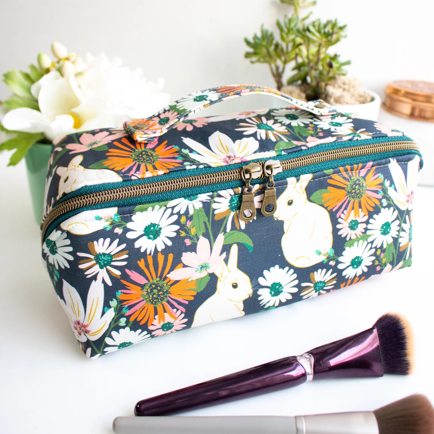 Floral and bunny-themed makeup bag with a brush on a white surface made from the Spring Roll Pouch sewing pattern from Love You Sew Patterns