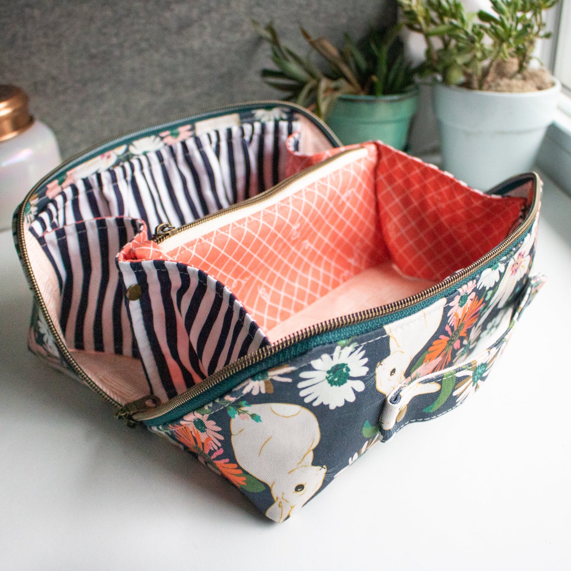 Multicolored fabric pouch with floral and animal pattern on a white surface made from the Spring Roll Pouch sewing pattern from Love You Sew Patterns