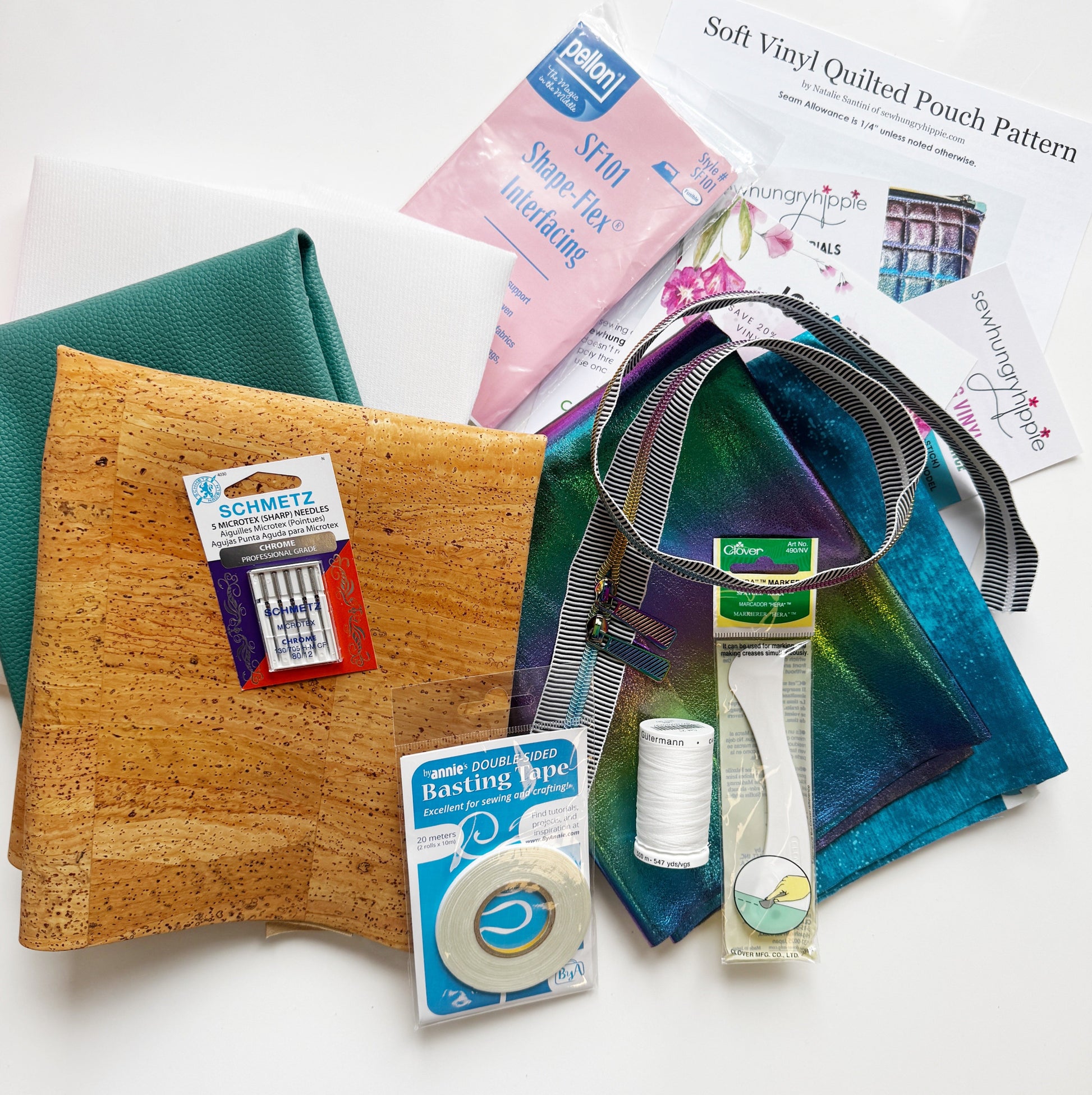 Collection of sewing supplies including a cork board, thread, scissors, and pattern paper on a white surface.