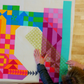 Natalie marking a colorful quilt with geometric blocks in the shape of a sewing machine on a wooden sewing table