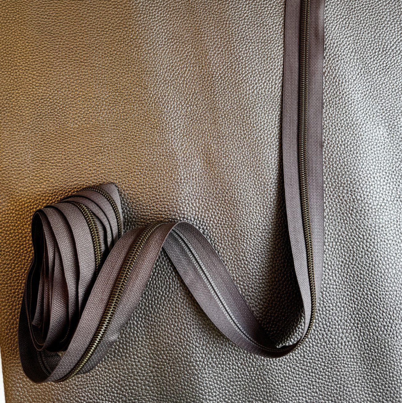 Strawberry Mocha #5 continuous zipper tape with bronze teeth paired with Taupe Moonglow vinyl. A coordinating combination for handmade handbags, wallets, backpacks, pouches, and other bag-making projects.