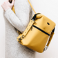 Yellow convertible backpack being held by a person on a white background