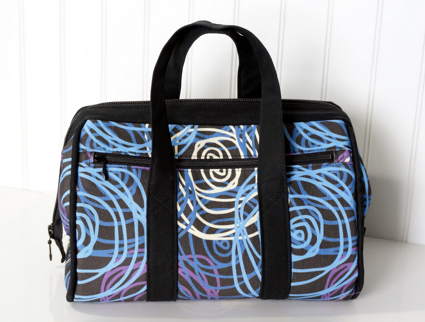 Patterned bag with black handles on a white surface