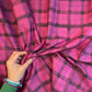 Hand holding a magenta pink and black artistic grid plaid cotton fabric for quilting, apparel, and sewing projects.