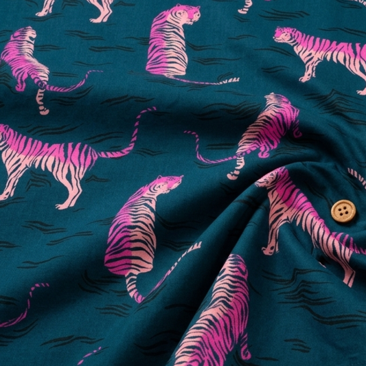 Pink tiger print cotton fabric on deep teal blue background by Ruby Star Society, shown in a soft draped close-up with flowing folds that highlight the smooth texture and retro animal print design for quilting, apparel, and sewing projects.