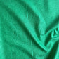 Draped and folded vibrant green fabric with a dark green malachite swirl pattern, showing the material's texture and sheen.
